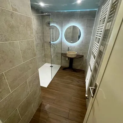 Salle de bain moderne avec douche à l'italienne, lavabo et miroir éclairé.