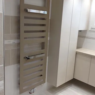 Porte-serviettes chauffant vertical et placard blanc dans une salle de bain moderne.